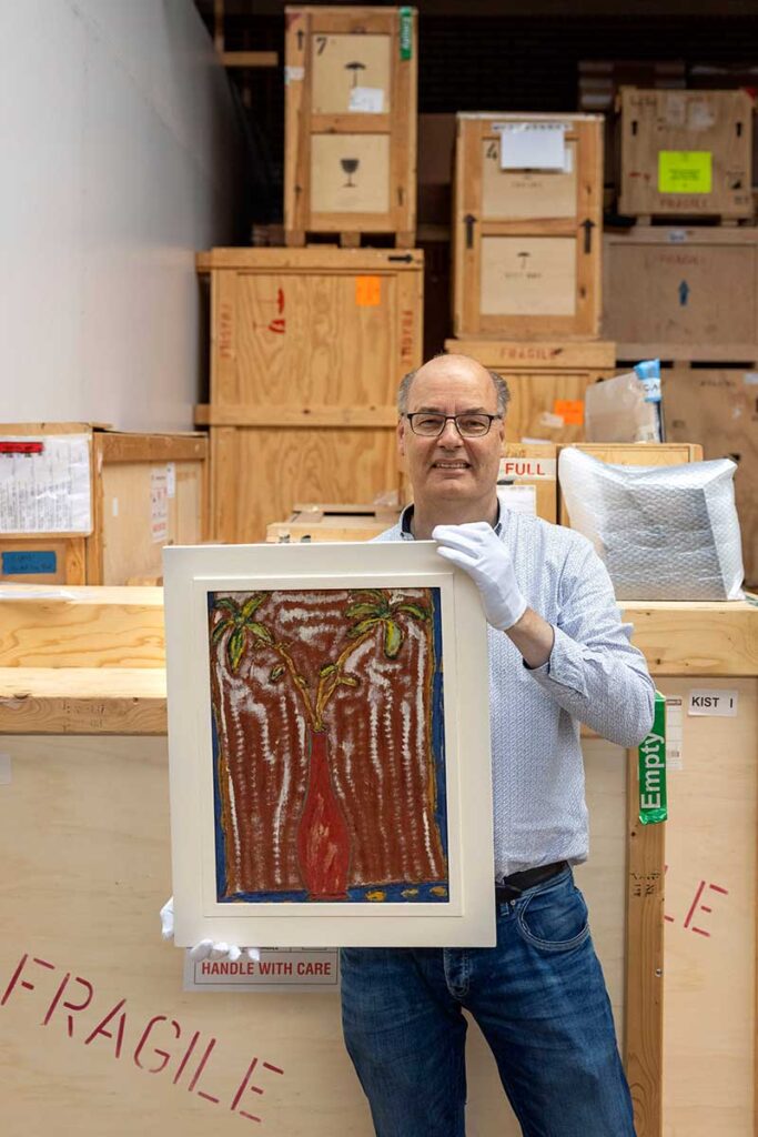 Arnold Ligthart met een schilderij uit zijn collectie